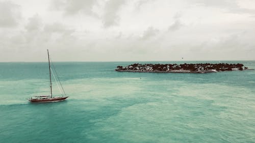 White Sail Boat on Sea Under White Sky