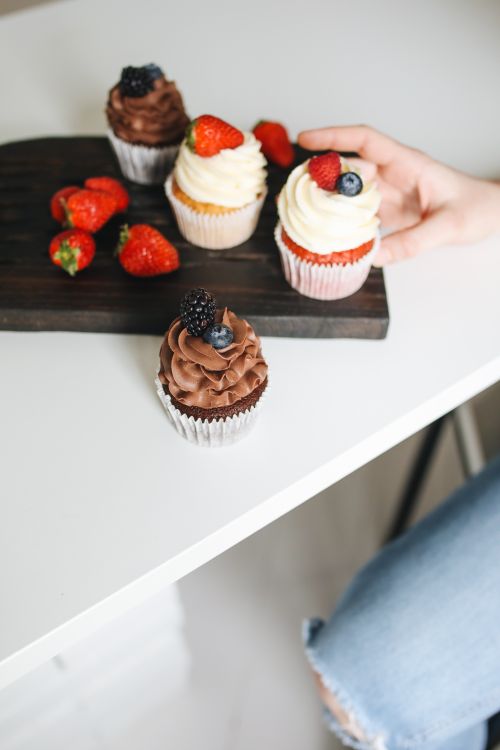 Free Close-up of delicious cupcakes topped with fresh berries on a wooden board. Stock Photo