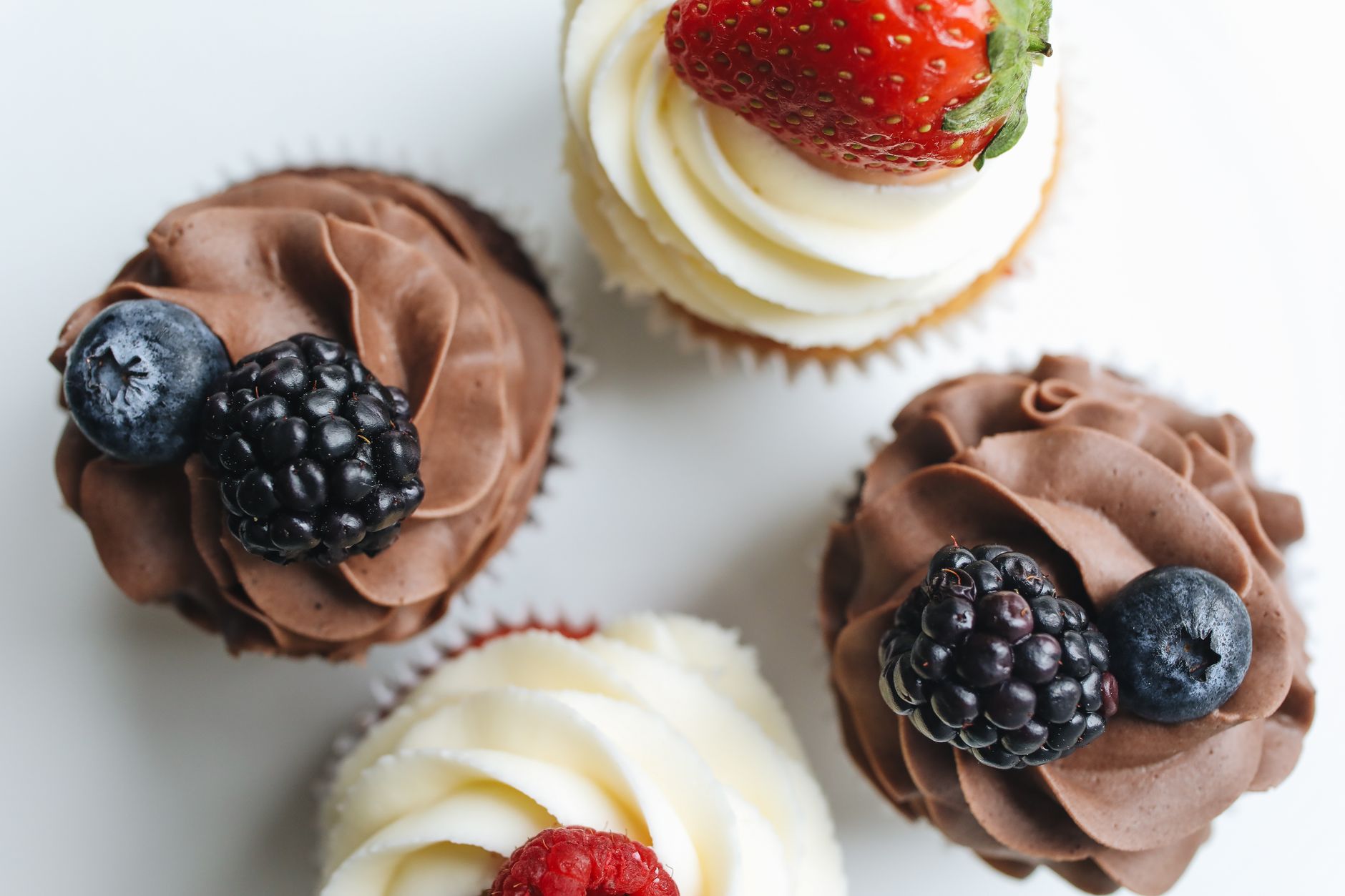 Cupcakes topped with strawberries on a cooling rack