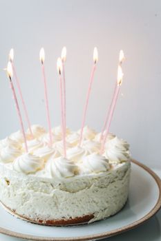 白色磨砂生日蛋糕摆在陶瓷盘上，蜡烛已经点燃，非常适合庆祝活动