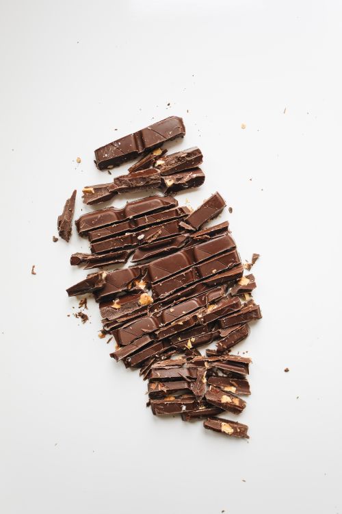 Free Indulge in the rich texture of broken chocolate pieces captured in a clean, minimalist setting. Stock Photo