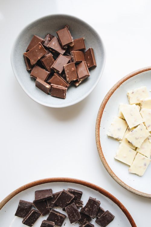 Free Top view of assorted milk, white, and dark chocolate pieces in ceramic bowls. Perfect for sweet indulgence. Stock Photo