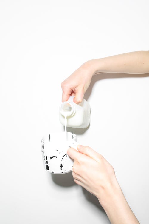 Person Pouring Milk On A Ceramic Mug