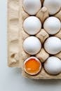 一盒白鸡蛋中，有一个破裂了，露出充满活力的蛋黄