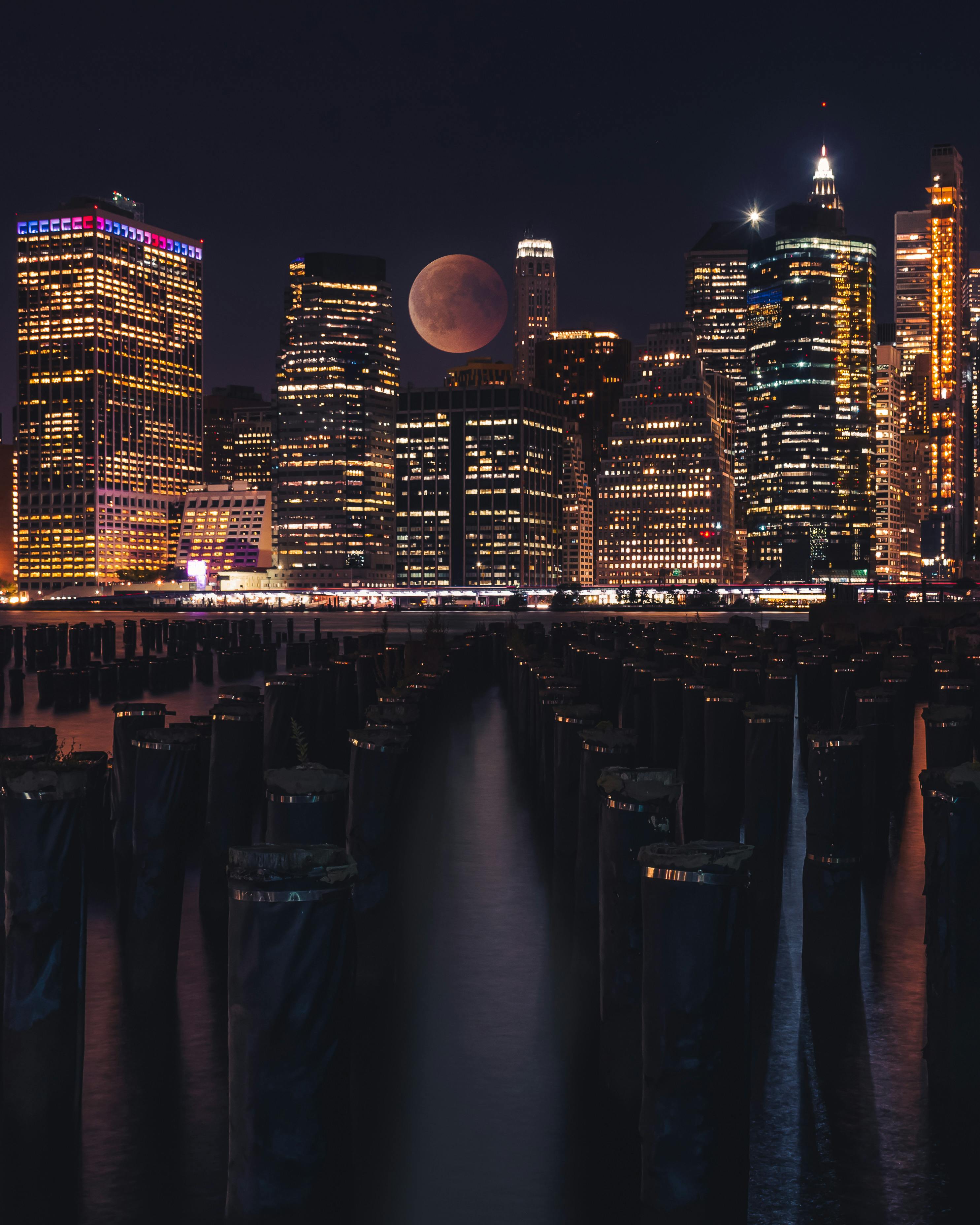 纽约的夜景，地平线上戏剧性的摩天大楼灯光与满月交相辉映