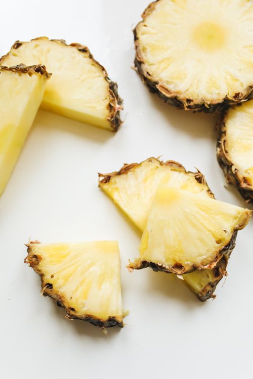 Fresh pineapple slices on a white surface — photo by Polina Tankilevitch on Pexels