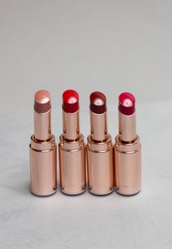 Four luxury lipsticks in copper tubes showcasing vibrant shades. Perfect for beauty enthusiasts.