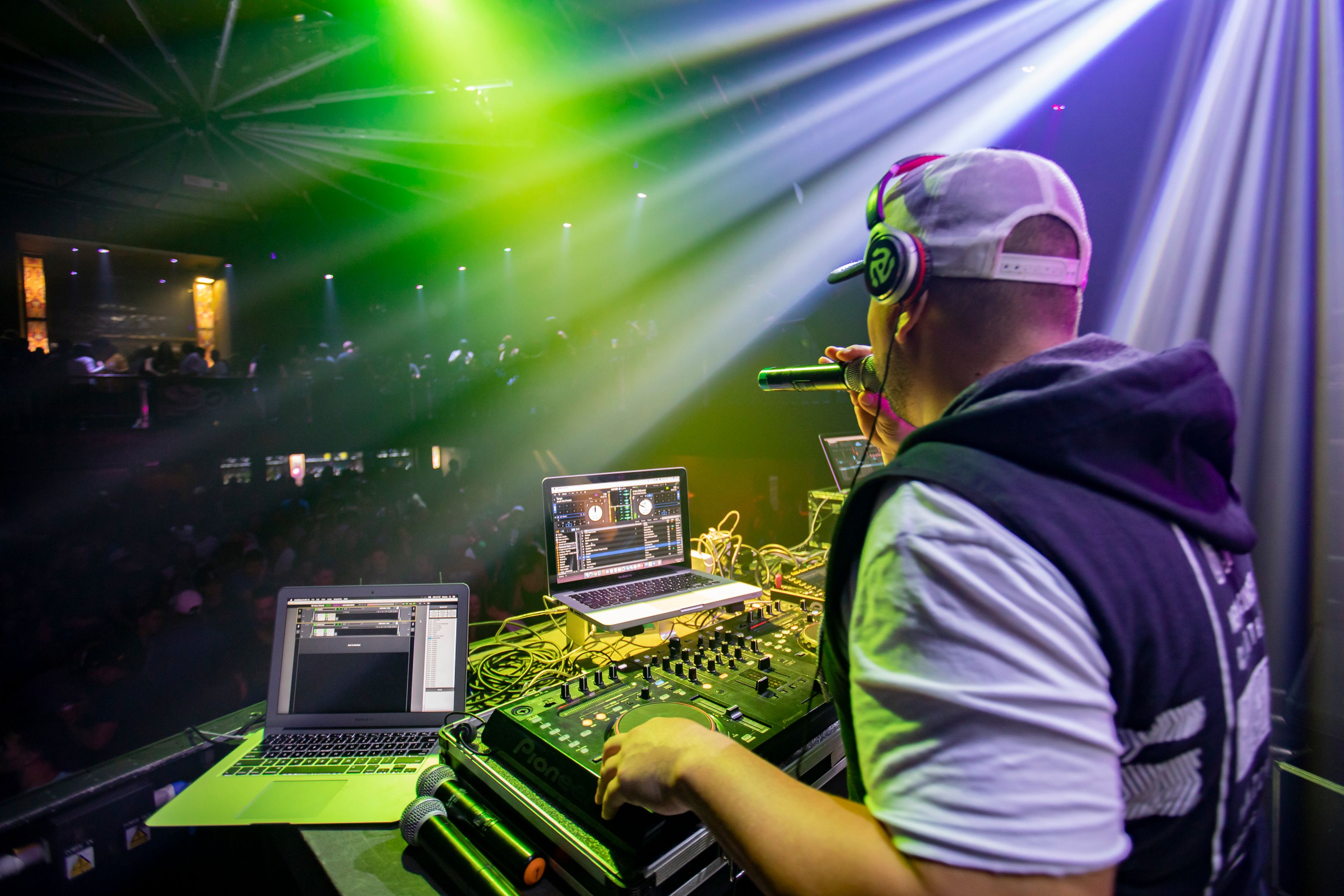 Energetic DJ performing live with dynamic lighting effects and an engaging crowd in a vibrant nightclub.