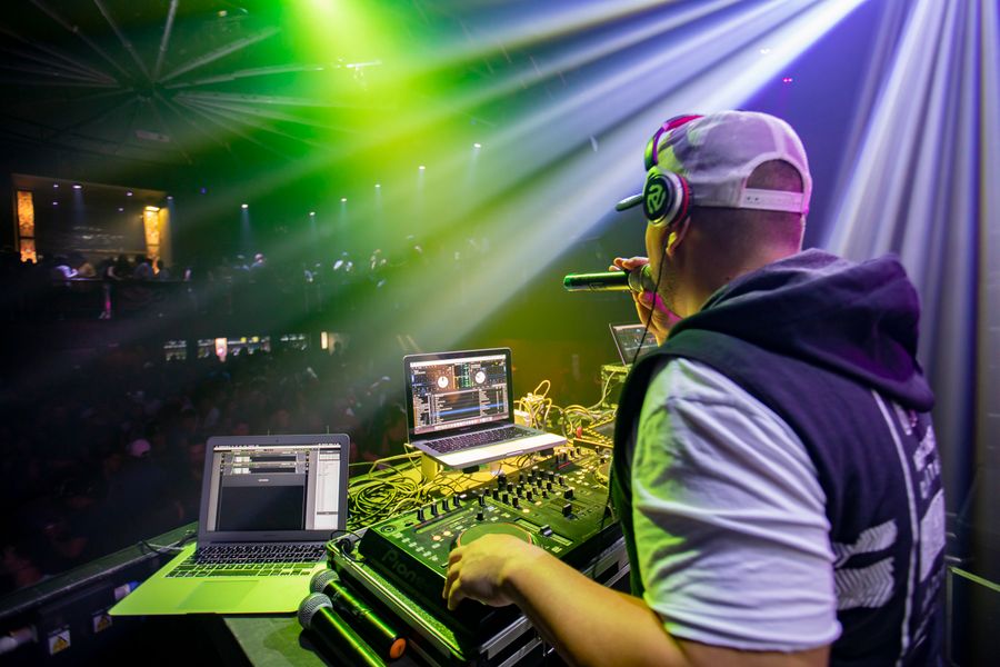 DJ en pleine performance sous des faisceaux verts et violets