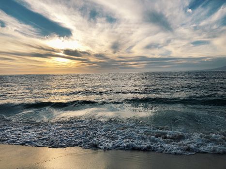 Peaceful ocean sunset with gentle waves at a tranquil beach.