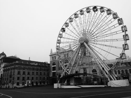 Free Black and white photo of a ferris wheel situated in a historical city square. Stock Photo