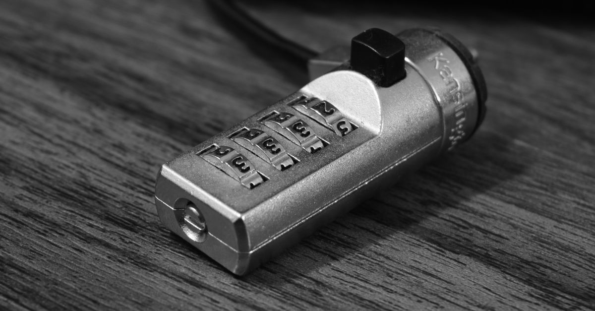 A close-up shot of a silver combination lock on a steel gate.
