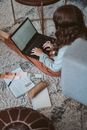 女人在家里用笔记本电脑工作，周围的地板上都是设计元素