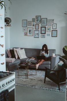 一位女士在时尚的客厅里放松，拿着智能手机，拥抱现代家居设计