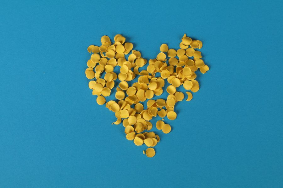 Golden confetti shaped like hearts scattered on a bright blue table