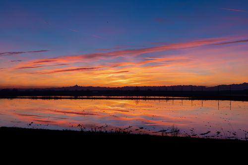 Free A breathtaking sunset over a lake with vivid colors and reflections creating a tranquil landscape scene. Stock Photo