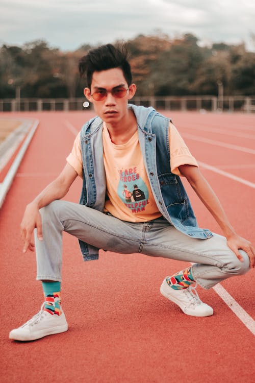 Foto profissional grátis de agachado, colete jeans, homem asiático