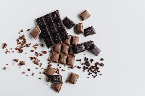 Free Artistic arrangement of dark and milk chocolate bars with crumbs on a white surface. Stock Photo