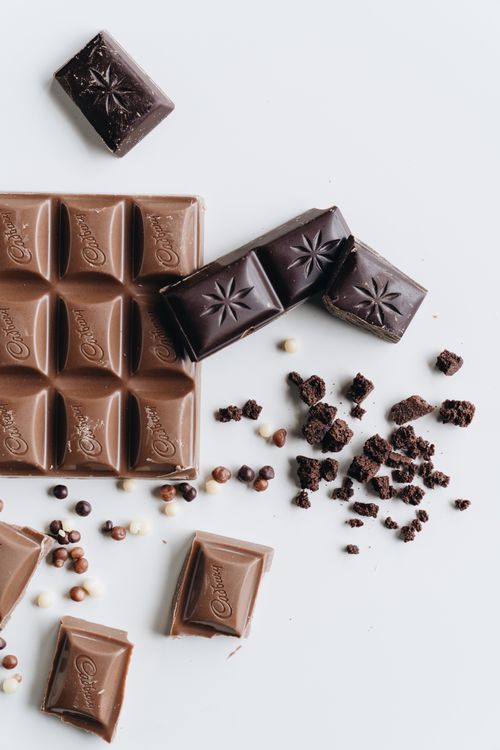 Free A delectable arrangement of milk and dark chocolate bars with crumbles on a pristine white surface. Stock Photo