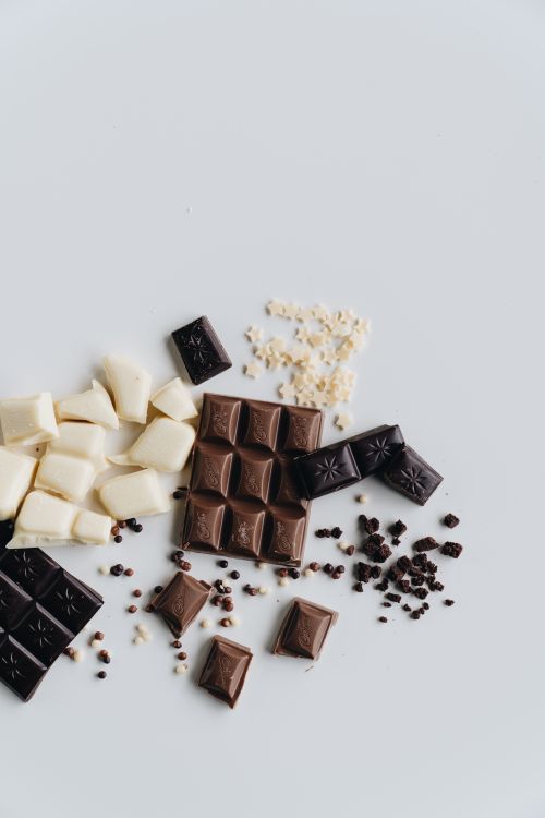 Free Flat lay of assorted chocolate pieces including dark and white chocolate against a clean white background. Stock Photo