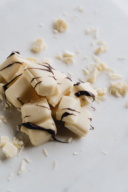Free Elegant pieces of white chocolate with dark drizzle scattered on a marble surface. Stock Photo