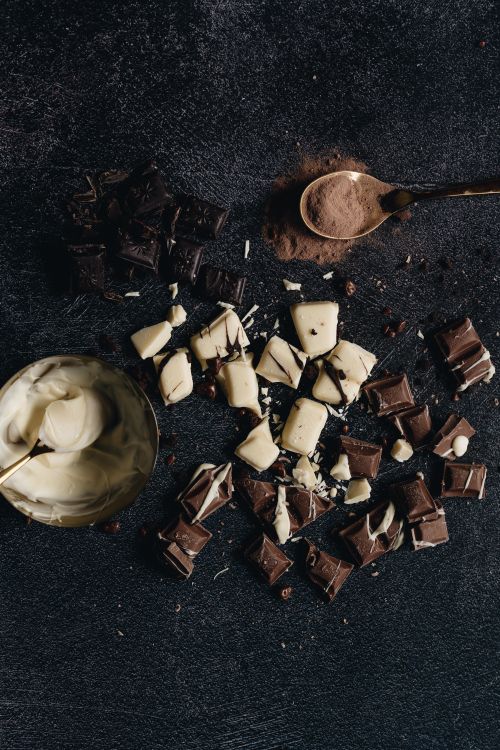 Free A creative arrangement of dark, milk, and white chocolate pieces with a cocoa spoon. Stock Photo