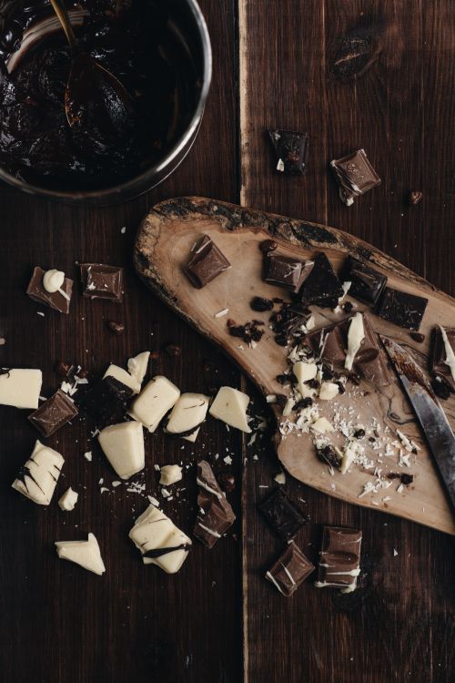 Free Top view of assorted chocolate pieces on a wooden cutting board, perfect for dessert indulgence. Stock Photo