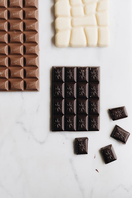 Close-Up Shot of Assorted Chocolate Bars on a White Surface