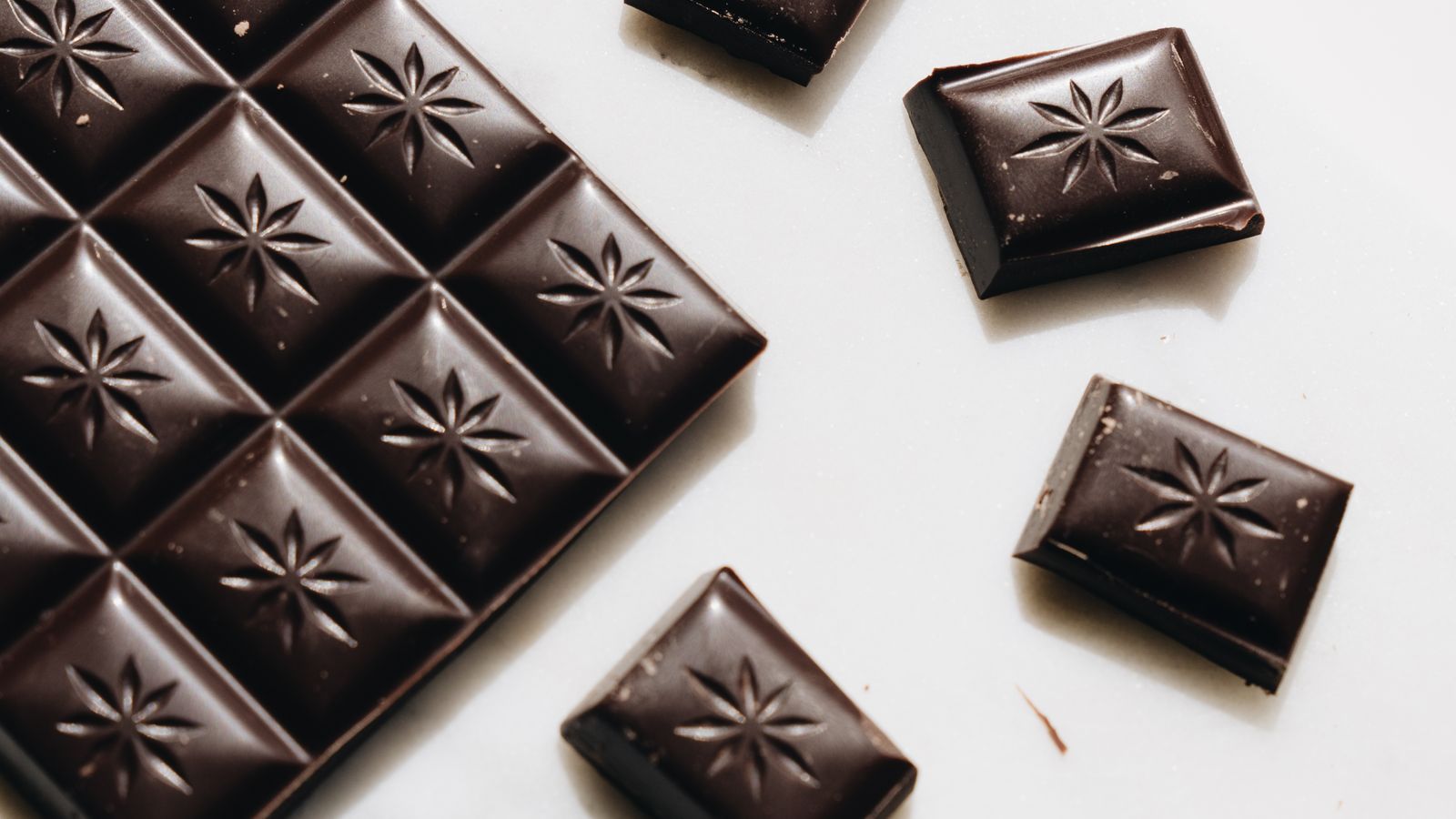 Close-up of dark chocolate pieces on a white surface — photo by alleksana on Pexels Close-up of dark chocolate pieces on a white surface