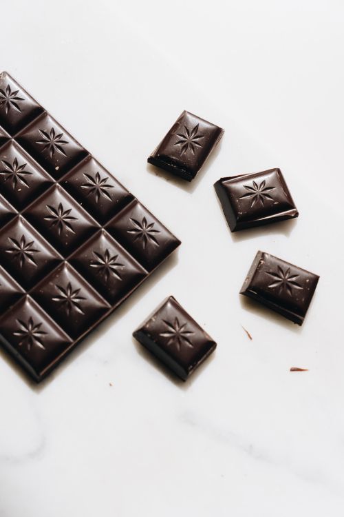 Free A close-up of delectable dark chocolate pieces on a white surface with elegant design. Stock Photo