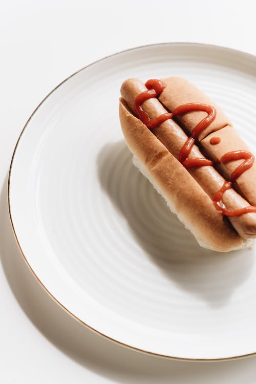 Free Close-Up Shot of a Hotdog Sandwich on a White Plate Stock Photo