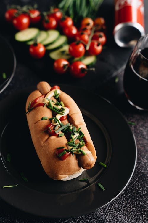 Hot Dog and Vegetable on Black Ceramic Plate