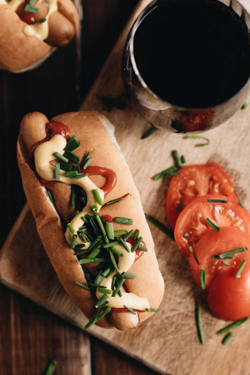 Hot Dog and Tomato on Wooden Board and Drink