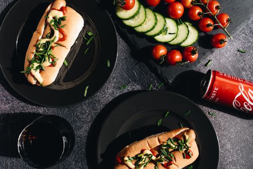 Free Savor gourmet hot dogs topped with fresh vegetables, served with a refreshing cola. Stock Photo