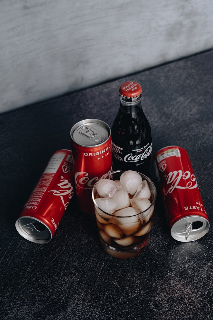 Photo Of Canned Soft Drinks Near Glass