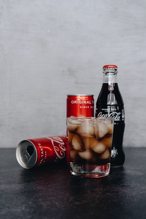 Free Chilled glass of cola with ice, surrounded by bottles and cans on a dark surface. Stock Photo