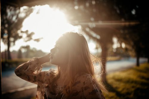 Free A woman with flowing hair enjoys the sunlight during golden hour outdoors. Stock Photo