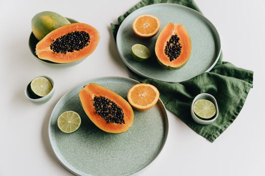 A vibrant still life featuring papaya, oranges, and limes on ceramic plates.