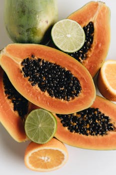 A vibrant arrangement of sliced papayas, lime, and orange, showcasing fresh tropical fruits.