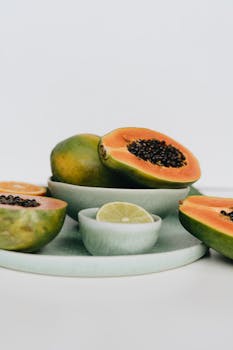 Vibrant sliced papaya and lime on pastel ceramic plates, showcasing tropical freshness.