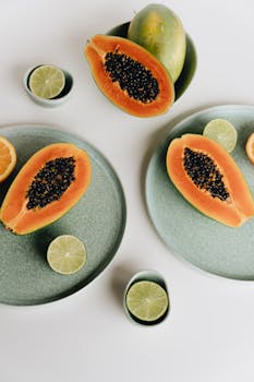 Vibrant image of sliced papaya and lime on pastel plates, highlighting freshness.