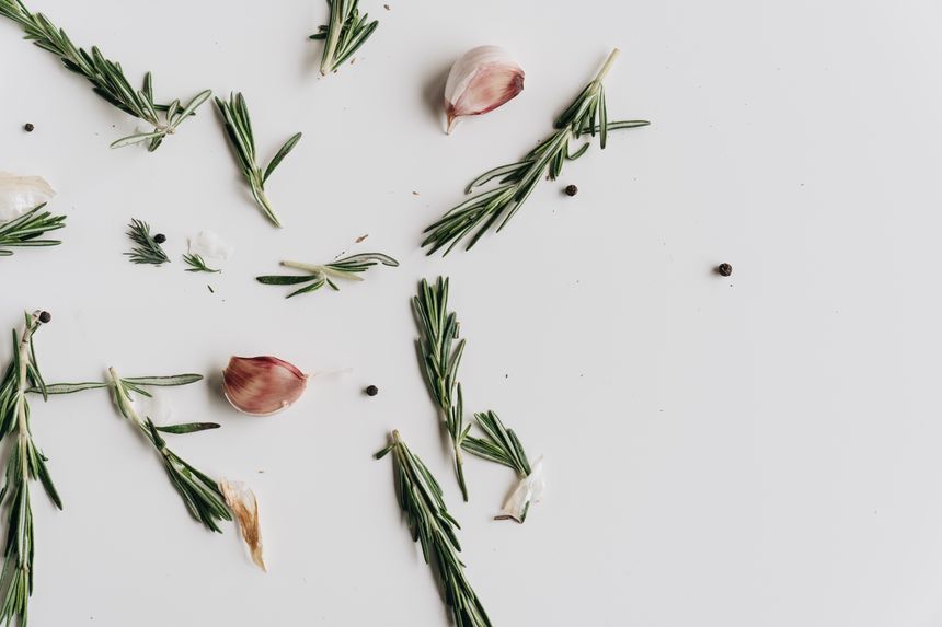 Herbs, garlic and peppercorns arranged on a white surface, photo by alleksana on Pexels
