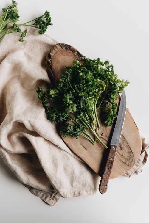 Free Top view of fresh parsley on a wooden board with a knife, perfect for culinary uses. Stock Photo