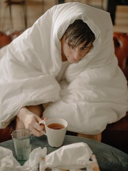 男人用毯子裹着一杯茶，营造出舒适的家庭氛围