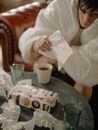 男人裹着毯子坐在纸巾和茶渍中，感觉很不舒服