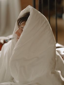 年轻人裹着带温度计的毯子，传达出休息与医疗保健的信息
