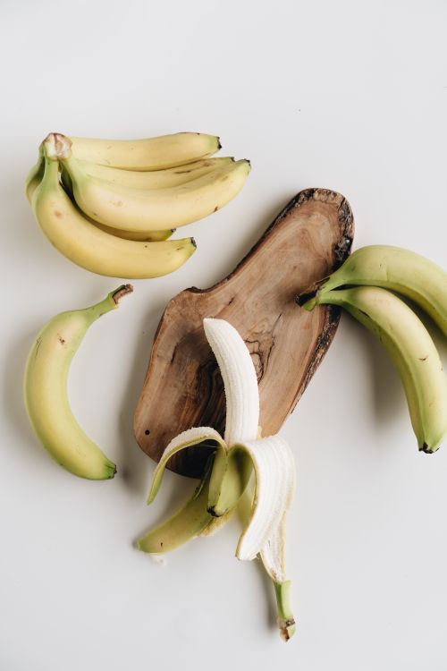 Free Top view of fresh bananas with peeled fruit on a rustic wooden board, perfect for healthy food themes. Stock Photo