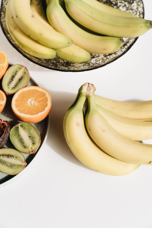Free Close-up view of fresh tropical fruits including bananas, kiwi, and orange slices. Stock Photo