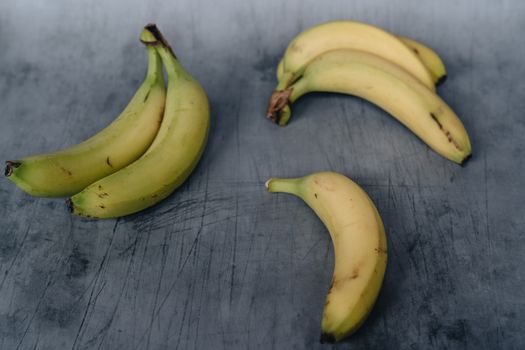 Unpeeled ripe bananas on shabby surface
