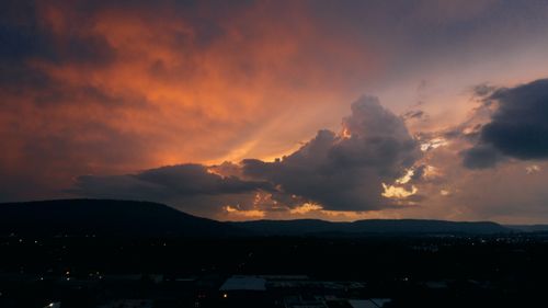 Free View of evening sky with vibrant pink clouds above mountain range and city Stock Photo